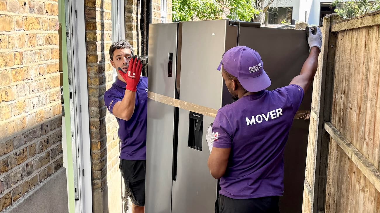Two removal specialists preparing to lift and manoeuvre a fridge safely during a London move