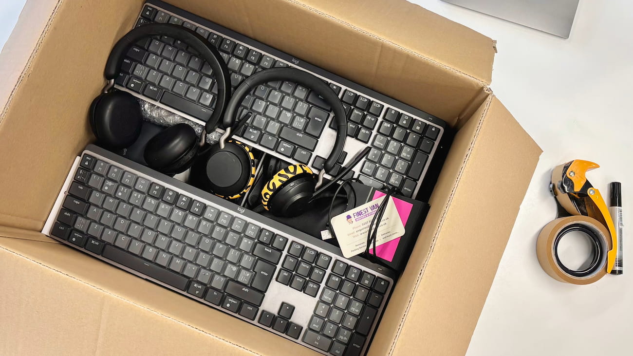 Open moving box packed with office electronics including keyboards, computer mice and accessories