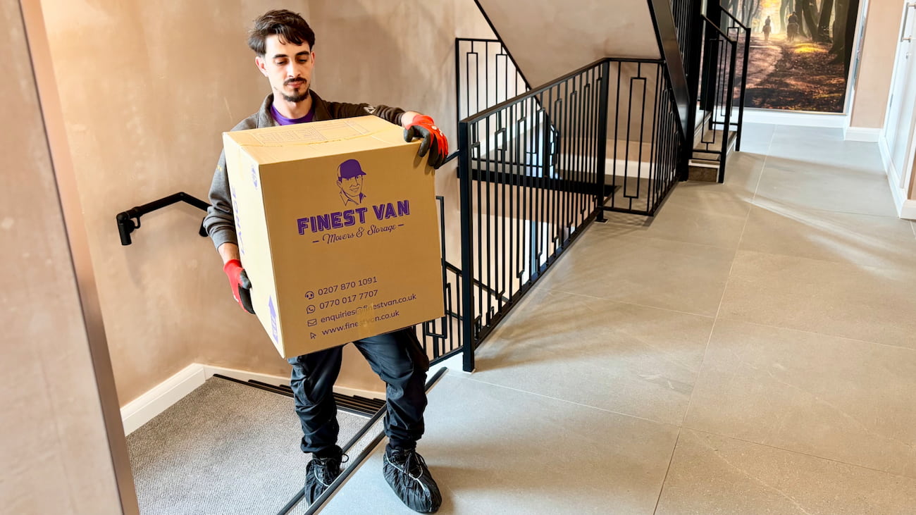 Removal specialist carrying moving box upstairs during flat move without a lift in London
