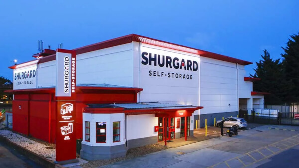 Exterior of Shurgard Self Storage in London at dusk with branded entrance and parking area